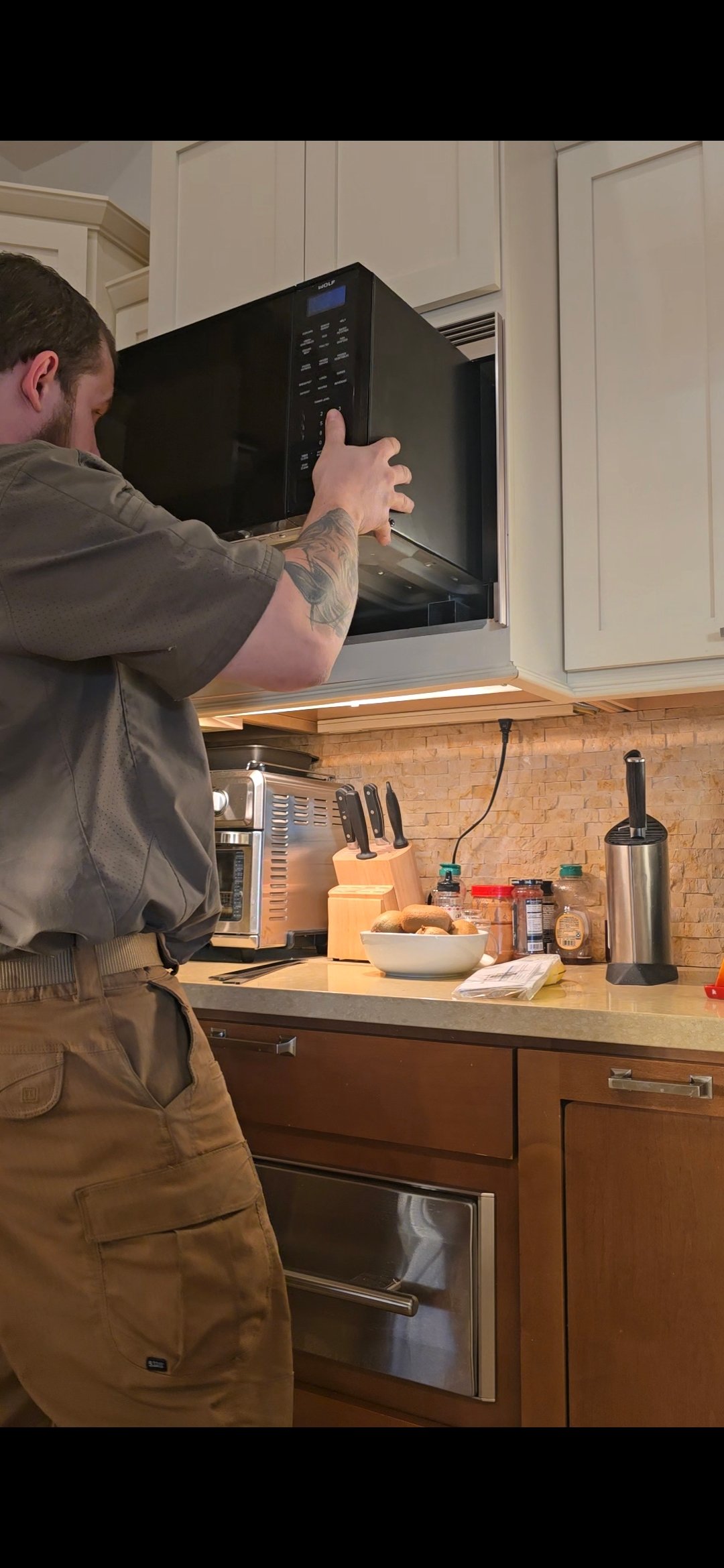 ProMaster technician servicing a built-in Wolf microwave in a Scottsdale kitchen