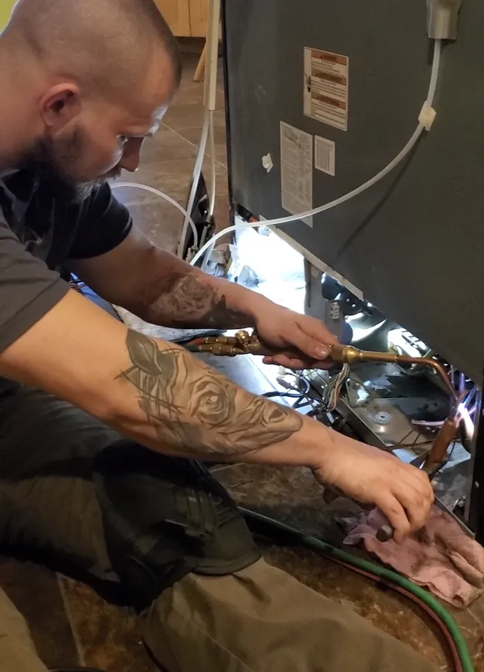 Technician servicing equipment under a commercial kitchen exhaust hood